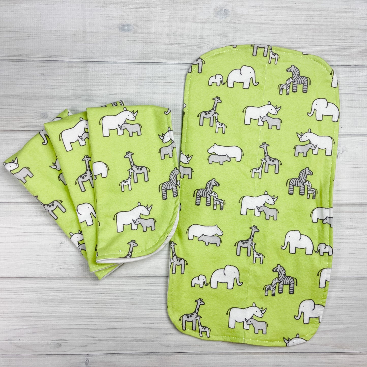 Green flannel burp cloths with elephants, hippopotamus, giraffes, zebras and rhinoceros adult and baby in white and gray.
