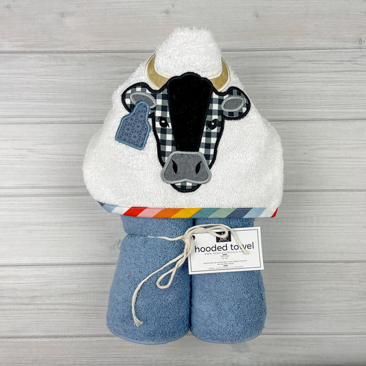 Medium blue hooded towel with black and white bull with horns and a tag embroidered on a white hood.  Binding is muted rainbow colors of red, pink, orange, yellow, teal , pale green, dust blue, light blue and white.