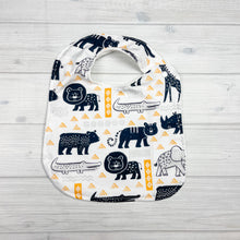 Load image into Gallery viewer, Generously sized infant/toddler bib. White background with black and white lions, giraffes, alligators, elephants and bears. accented with yellow and light gray geometric shapes. 
